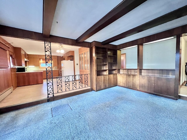 spare room with beam ceiling, light carpet, wooden walls, and baseboard heating