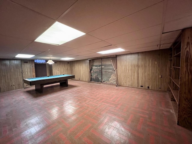 recreation room with a paneled ceiling, pool table, and wooden walls