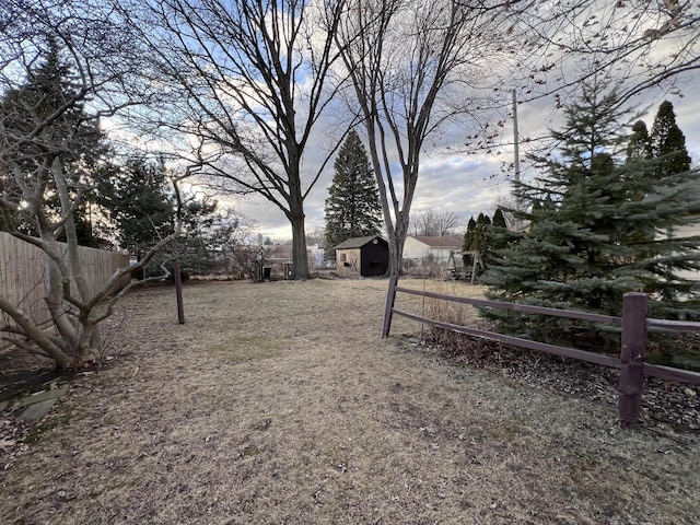 view of yard featuring an outbuilding, a storage unit, and fence