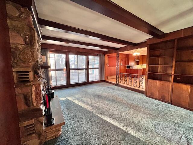 carpeted living area with beam ceiling and wood walls