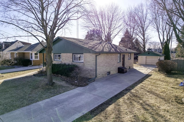 view of side of home featuring a garage, fence, a yard, an outdoor structure, and brick siding