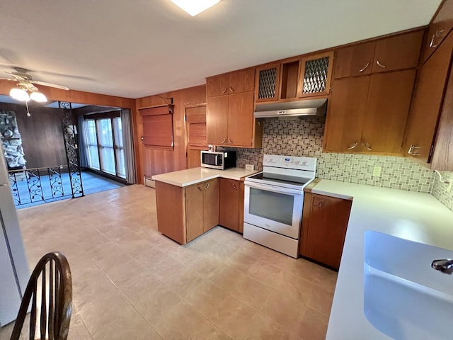 kitchen featuring stainless steel microwave, electric range, a sink, a peninsula, and under cabinet range hood