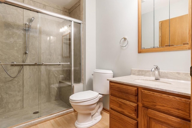 bathroom with a shower stall, vanity, toilet, and wood finished floors