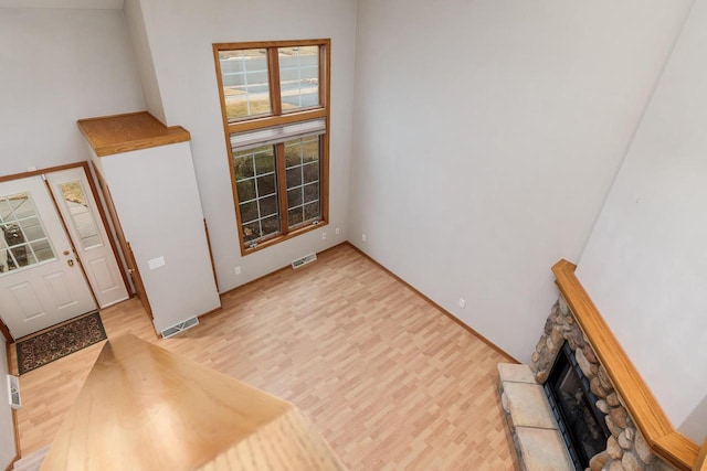 interior space with a stone fireplace, light wood-type flooring, and visible vents