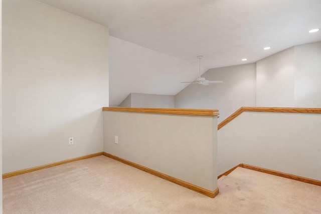 spare room featuring light colored carpet, vaulted ceiling, and baseboards