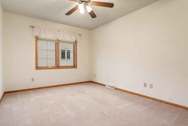 spare room with baseboards, a ceiling fan, visible vents, and light colored carpet