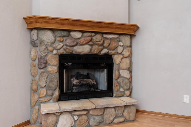 room details with baseboards, wood finished floors, and a stone fireplace