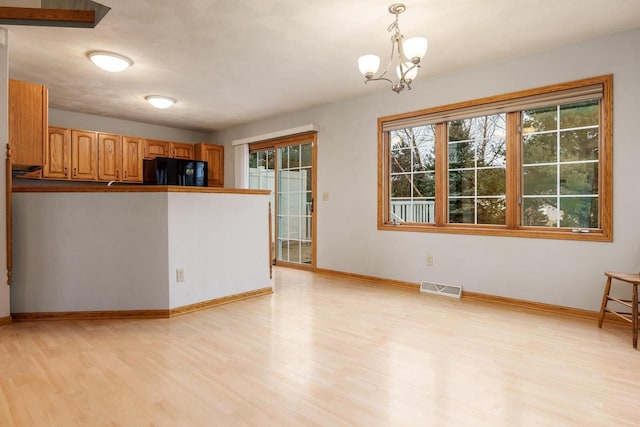 kitchen featuring baseboards, black refrigerator, visible vents, and light wood-style floors