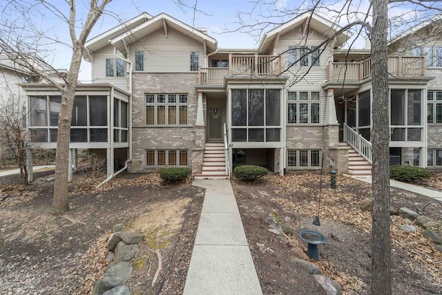 view of front facade with a sunroom, brick siding, and a balcony