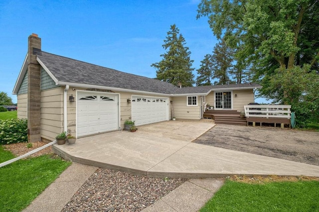 ranch-style house with a deck, a garage, concrete driveway, roof with shingles, and a chimney