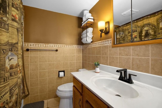 full bath featuring a wainscoted wall, tile walls, visible vents, toilet, and vanity