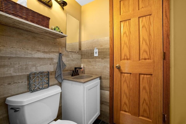 bathroom with vanity, toilet, and tile walls