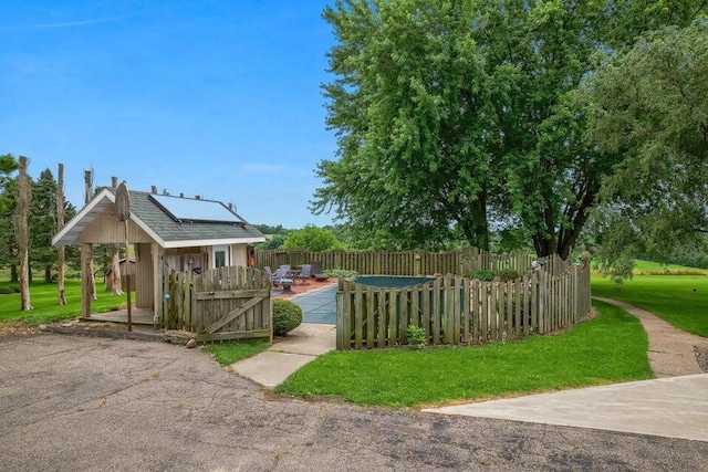 exterior space with an outbuilding, a lawn, fence, and roof mounted solar panels