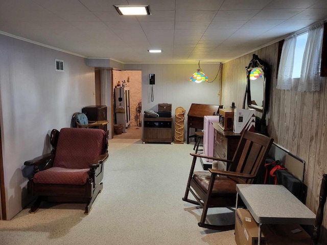 interior space with wood walls, carpet flooring, visible vents, water heater, and ornamental molding