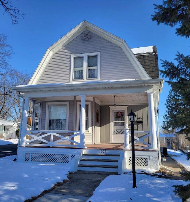 dutch colonial featuring roof with shingles, a porch, and a gambrel roof