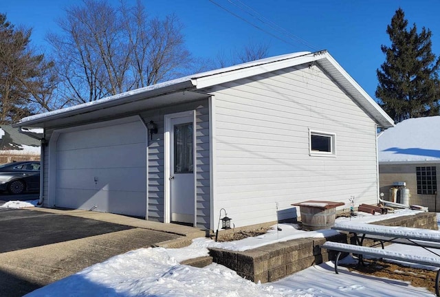 snow covered property featuring a garage and driveway