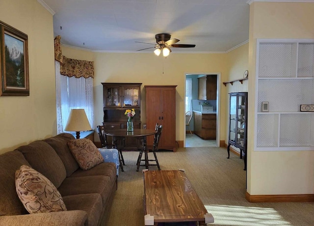 living room with light carpet, ceiling fan, baseboards, and crown molding