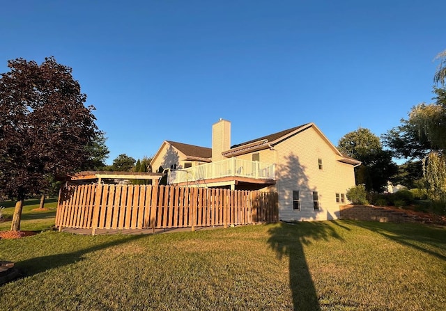 back of property with a lawn, a chimney, and fence