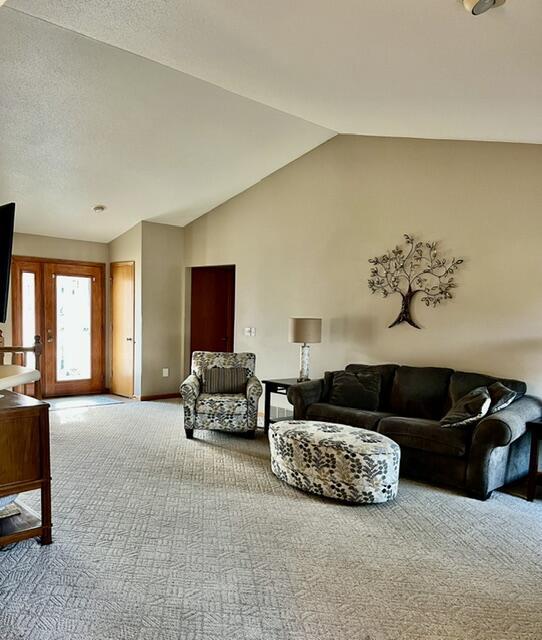 carpeted living room featuring vaulted ceiling, a textured ceiling, and baseboards