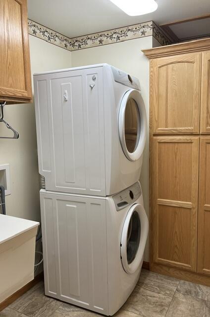 laundry area with stacked washer / dryer, a sink, and cabinet space