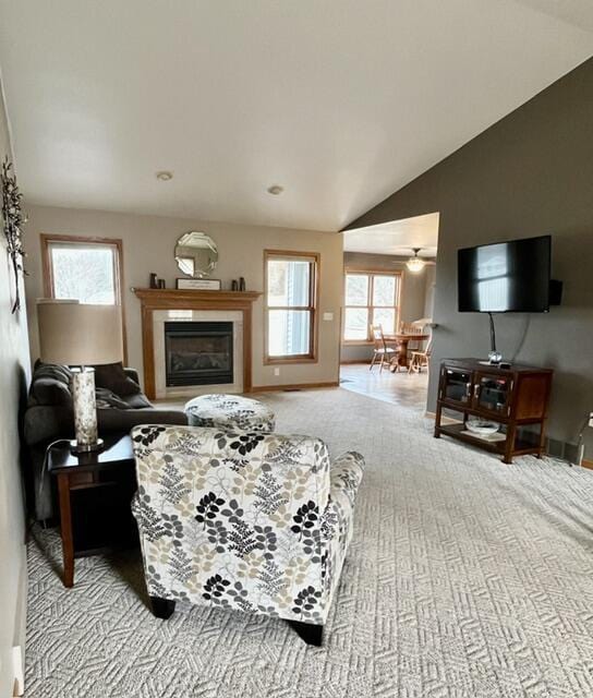 living area featuring carpet floors, a glass covered fireplace, vaulted ceiling, and baseboards