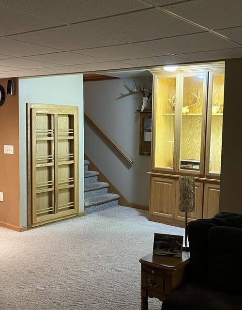 living room with carpet floors, stairs, baseboards, and a drop ceiling