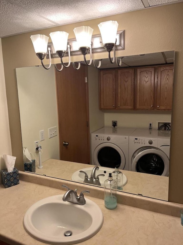 laundry area with a textured ceiling, washer and clothes dryer, a sink, and a notable chandelier