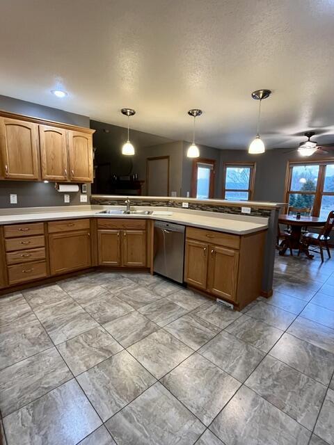 kitchen featuring brown cabinetry, light countertops, dishwasher, and a sink