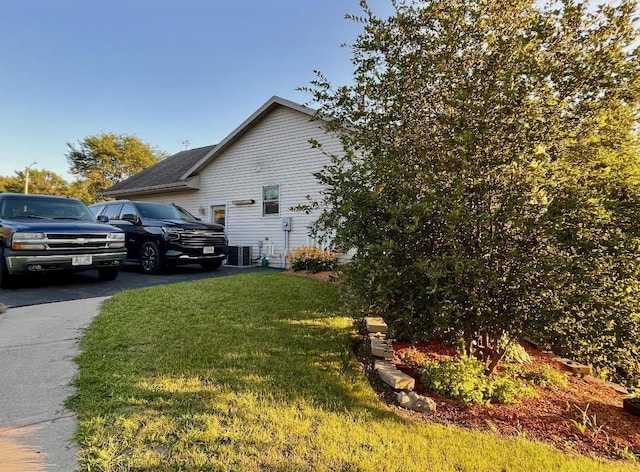 view of property exterior with a lawn and central air condition unit