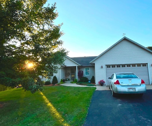 ranch-style house with a garage, aphalt driveway, and a front lawn