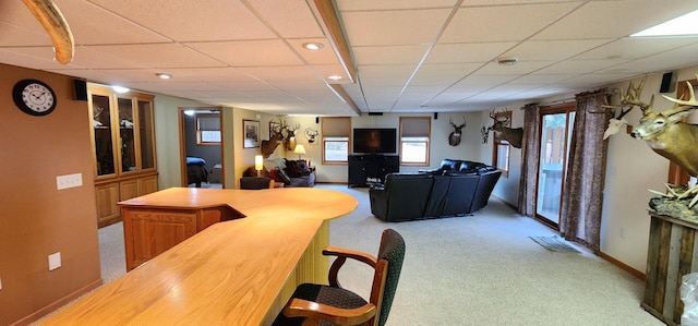 interior space with baseboards, a paneled ceiling, and light colored carpet