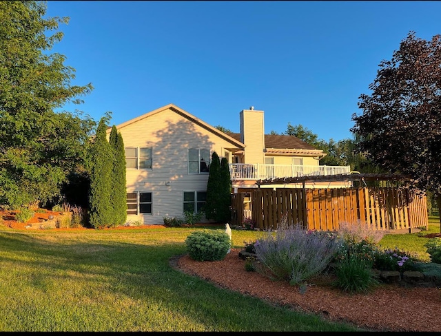 rear view of house featuring a lawn and a chimney