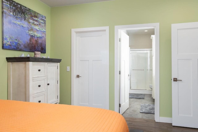 bedroom with ensuite bathroom, baseboards, and wood finished floors