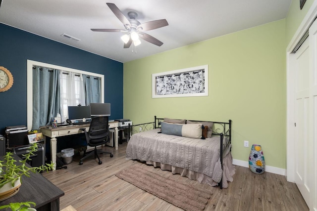 bedroom featuring visible vents, ceiling fan, baseboards, and wood finished floors