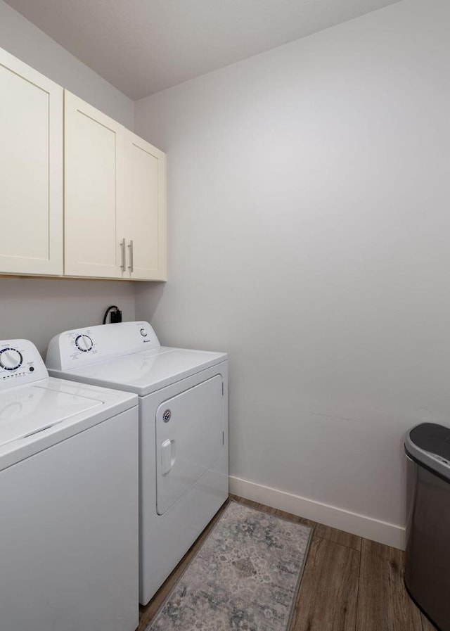 washroom featuring cabinet space, baseboards, washer and dryer, and wood finished floors