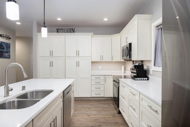 kitchen with light wood finished floors, hanging light fixtures, stainless steel appliances, light countertops, and a sink