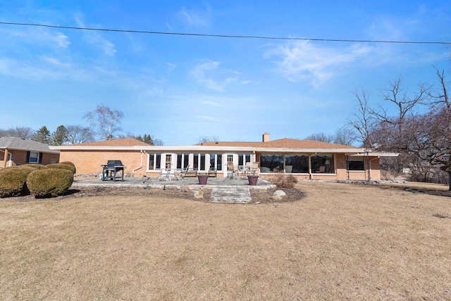 back of house featuring a patio area, a chimney, and brick siding