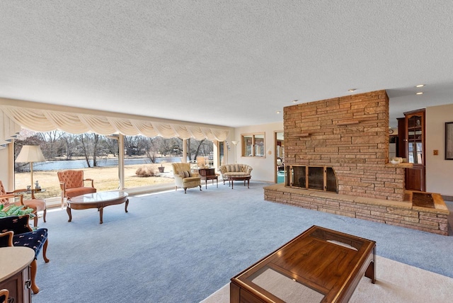 living area with recessed lighting, a textured ceiling, a stone fireplace, and carpet flooring