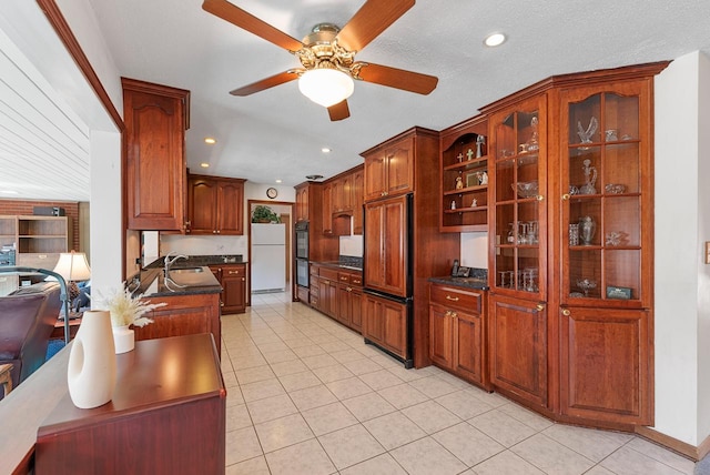 kitchen featuring dark countertops, paneled refrigerator, freestanding refrigerator, dobule oven black, and a sink