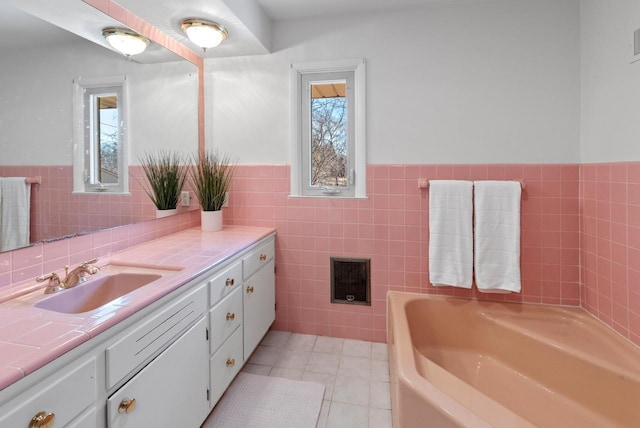 full bathroom featuring tile patterned flooring, tile walls, a wainscoted wall, a bath, and vanity