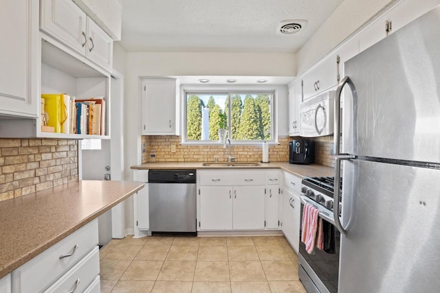 kitchen with visible vents, a sink, stainless steel appliances, white cabinets, and light countertops