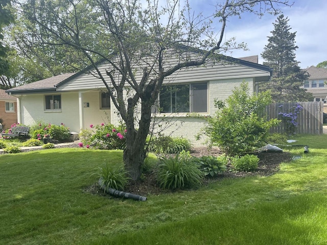 view of front of house with brick siding, a front lawn, and fence