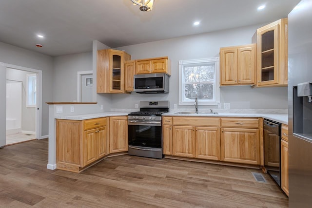 kitchen featuring light countertops, visible vents, light wood-style flooring, appliances with stainless steel finishes, and a sink