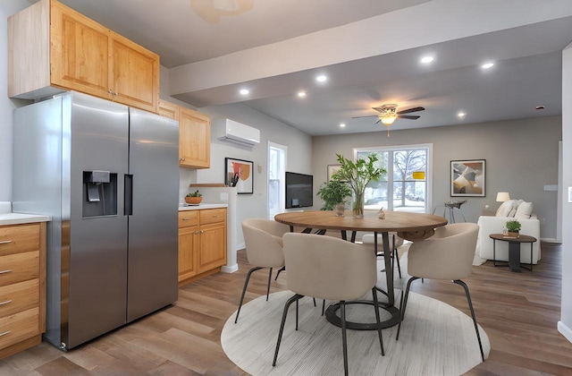 kitchen with an AC wall unit, light brown cabinets, stainless steel refrigerator with ice dispenser, and light wood finished floors