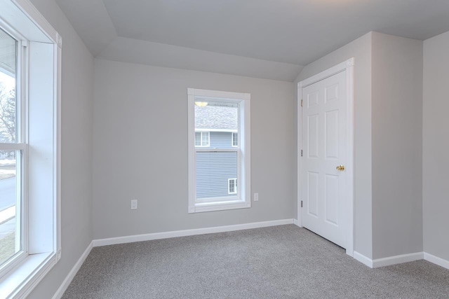 empty room featuring carpet, lofted ceiling, and baseboards