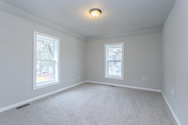 spare room featuring baseboards, carpet flooring, visible vents, and a healthy amount of sunlight