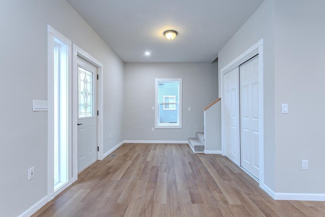 entrance foyer featuring light wood-style floors, stairs, and baseboards