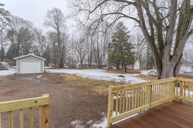 yard layered in snow with an outbuilding, a deck, and a detached garage