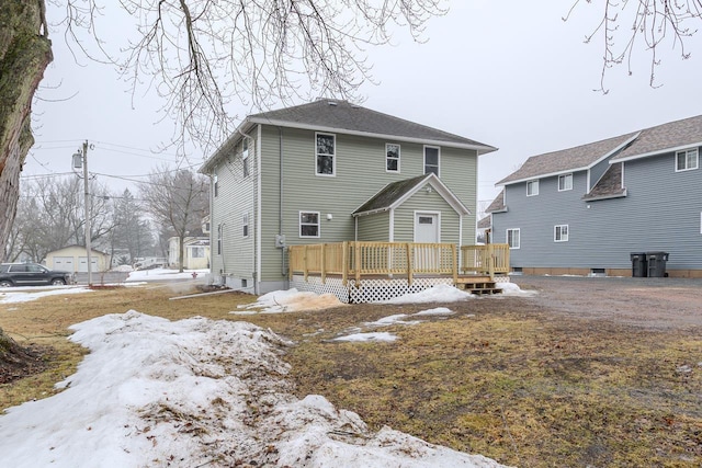 snow covered back of property featuring a deck