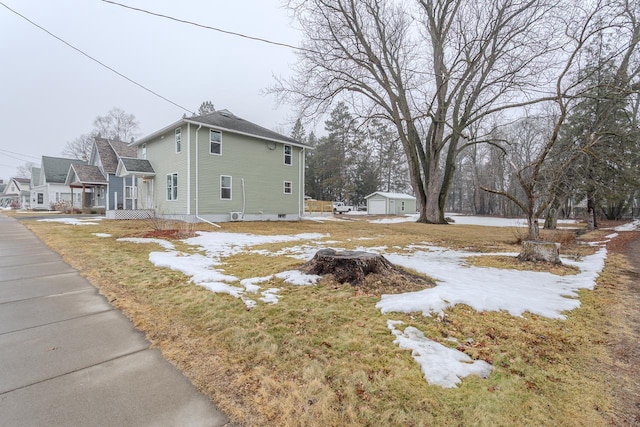 view of snow covered exterior featuring an outbuilding and a detached garage